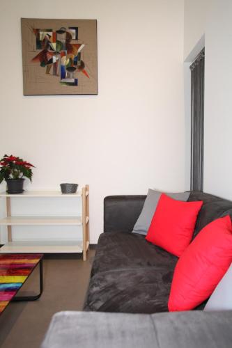 a living room with a couch with red pillows at Résidence Beauvoir le Mont-Saint-Michel (9 gîtes de 2 à 5 personnes) in Beauvoir
