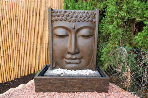 a statue of a face is sitting in a garden at Ashanti Garden Luxury Short Term Rental Duplex Altea in La Nucía