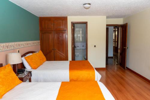 a bedroom with two beds with orange and white sheets at Hotel El Aerolito in Santa Rosa de Viterbo