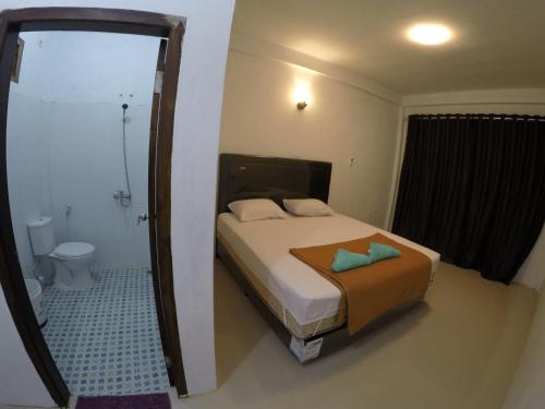 ein Schlafzimmer mit einem Bett und ein Badezimmer mit einer Toilette in der Unterkunft Iboih Malini Bungalow in Sabang
