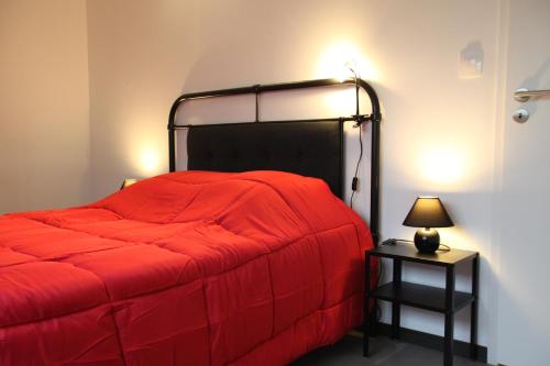 a bedroom with a red bed with a lamp on a table at Résidence Beauvoir le Mont-Saint-Michel (9 gîtes de 2 à 5 personnes) in Beauvoir