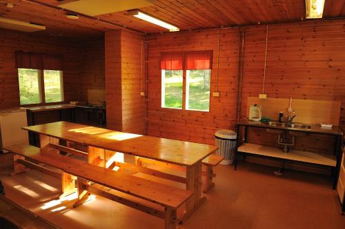 uma sala de jantar com uma mesa de madeira e bancos em Hännilänsalmi Camping em Viitasaari