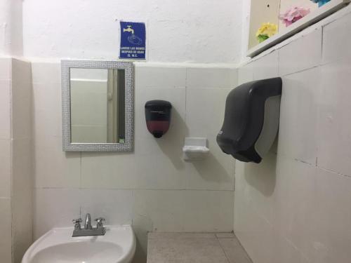 a bathroom with a sink and a mirror and a toilet at Hostal La Concordia in Ciudad Valles