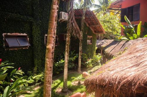a house with a straw roof next to a garden at Hotel Porto do Zimbo in Morro de São Paulo