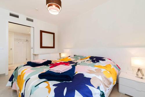 アルファス・デル・ピにあるAshanti Club Luxury Holiday Apartmentのベッドルーム1室(カラフルな毛布付きのベッド1台付)