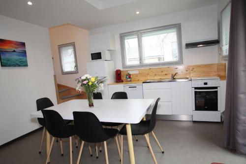 a kitchen with a white table and black chairs at Résidence Beauvoir le Mont-Saint-Michel (9 gîtes de 2 à 5 personnes) in Beauvoir