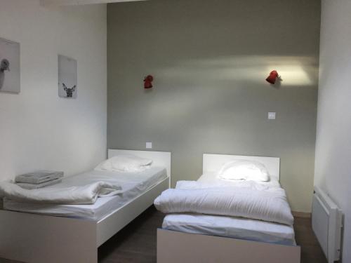 two beds in a room with white sheets at La cathare appartement in Lézignan-Corbières