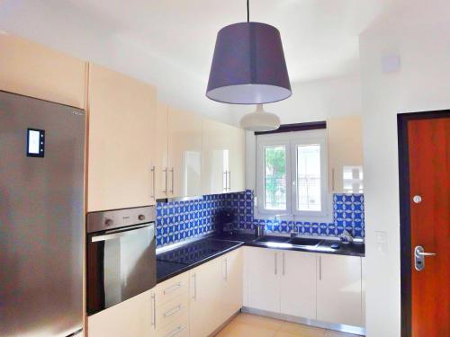 a kitchen with white cabinets and a blue tiled wall at Polychrono Nikos Apartment in Polychrono