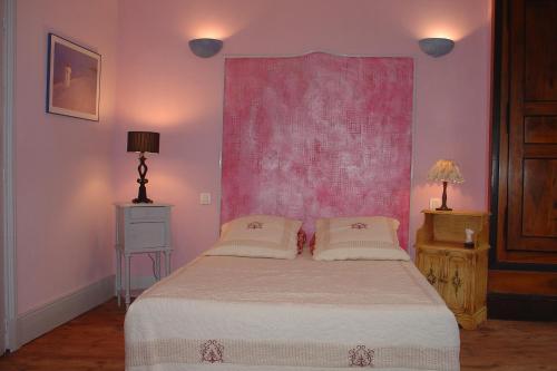 a bedroom with a bed with a pink wall at L Echarpe d Iris in Montpeyroux