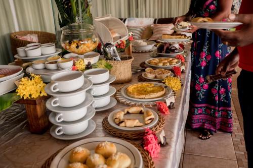 a long table filled with food and plates of food at Hotel Porto do Zimbo in Morro de São Paulo
