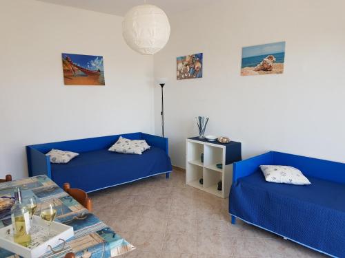 a room with two blue beds and a table at Punta Grande - Scala dei Turchi in Realmonte