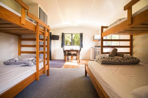 a bedroom with two bunk beds and a desk at Stratford Motel & Holiday Park in Stratford