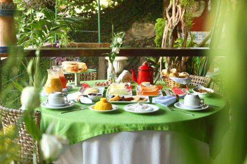 a table with a green table cloth with food on it at Pousada do Amparo in Olinda