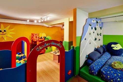 a childs play room with a rock wall and a slide at Naturhotel Die Waldruhe GmbH in Chienes