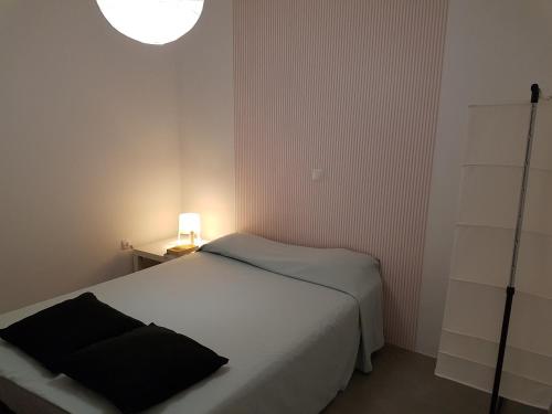 a small bedroom with a white bed and a lamp at Casa Io - Djeu in Mindelo