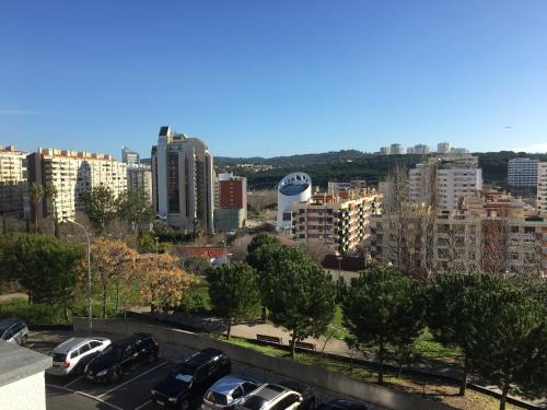 a city with cars parked in a parking lot at Apartamento novo muito confortável com vista Rio in Algés