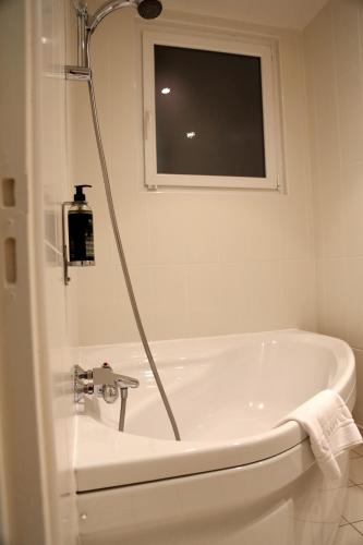 a bathroom with a bath tub with a window at Hotel Le Sevigne - Sure Hotel Collection by Best Western in Rennes