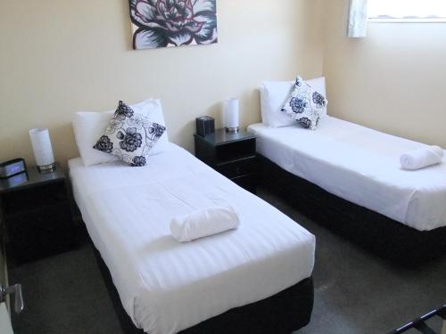 two beds in a room with white sheets and pillows at Abbella Lodge Motel in Christchurch
