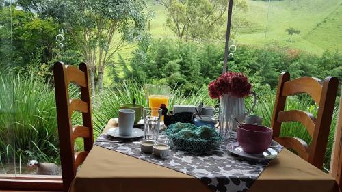 a table with food and drinks on it with a window at Pousada Vale Monte Azul in Santo Antônio do Pinhal