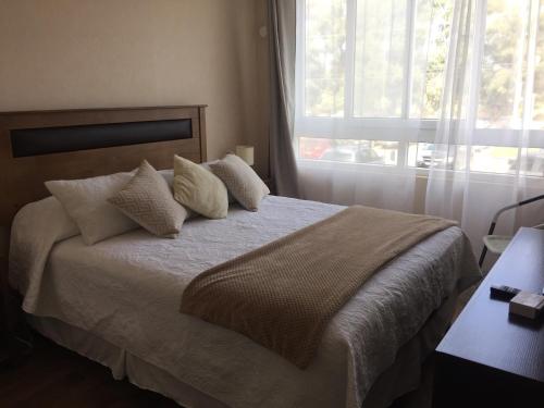 a bedroom with a bed with pillows and a window at Apartamento Terrazas del Sol in La Serena