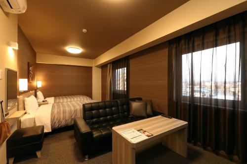 a hotel room with a bed and a couch and a table at Hotel Route-Inn Shinshiro in Shinshiro