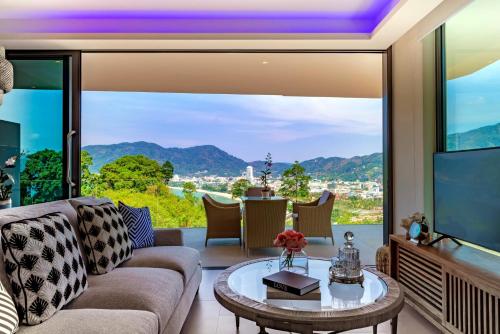 a living room with a couch and a large window at Patong Heights in Patong Beach