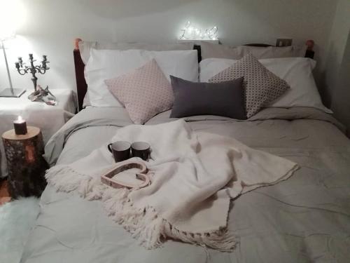 a bed with a blanket and two cups on it at Elison-on the lake B&B in Sauris