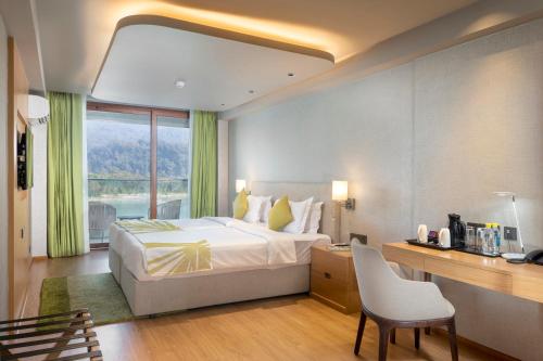 a hotel room with a bed and a desk and a window at Modi Yoga Retreat Rishikesh in Rishīkesh