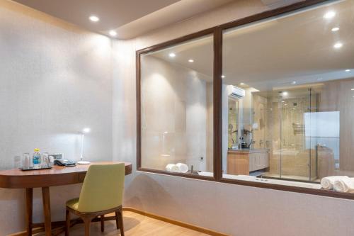 a bathroom with a desk and a glass window with a shower at Modi Yoga Retreat Rishikesh in Rishīkesh