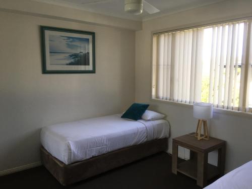 a small bedroom with a bed and a window at Town Beach Beachcomber Resort in Port Macquarie