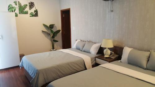 a hotel room with two beds and a table with a lamp at Tre Việt Tuy Hòa Hotel in Tuy Hoa