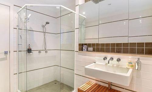 a white bathroom with a sink and a shower at BEACHFRONT Beauty! in Gold Coast