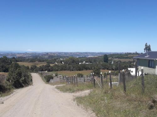 a dirt road next to a house on a hill at Agroturismo los Colihues in Castro