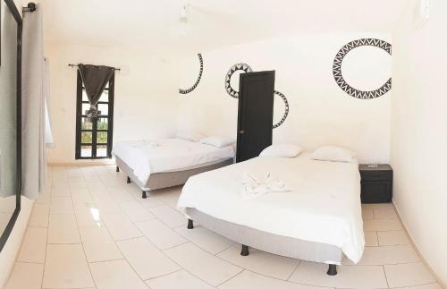 two beds in a room with white walls at Zoola San Pedro Atitlan in San Pedro La Laguna