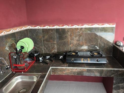 a kitchen counter with a sink and a stove at DSTAY Kost Bali in Jimbaran