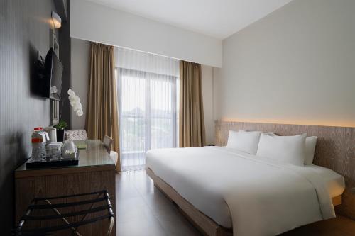 a bedroom with a large white bed and a window at Hotel Santika Siligita Nusa Dua in Nusa Dua