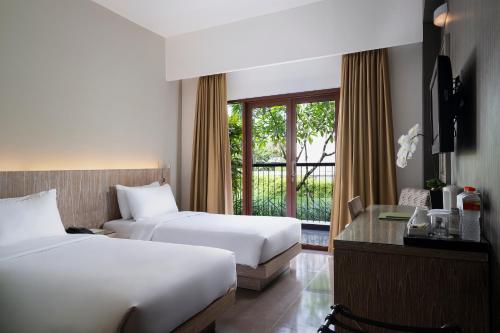 a hotel room with two beds and a window at Hotel Santika Siligita Nusa Dua in Nusa Dua