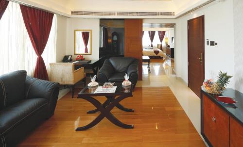 a living room with a black couch and a table at Windsor Rajadhani Hotel in Trivandrum