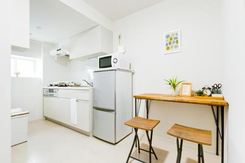 een keuken met een witte koelkast en een houten tafel bij Momodani House 501 in Osaka