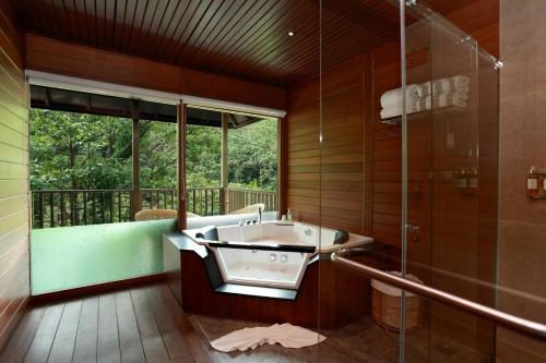 a bathroom with a tub and a glass shower at The IBNII - Eco Luxury Resort in Madikeri