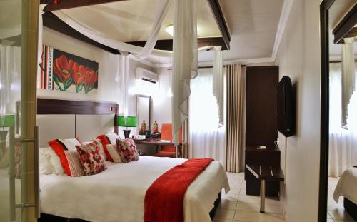um quarto com uma cama grande e almofadas vermelhas e brancas em BON Hotel Empangeni em Empangeni