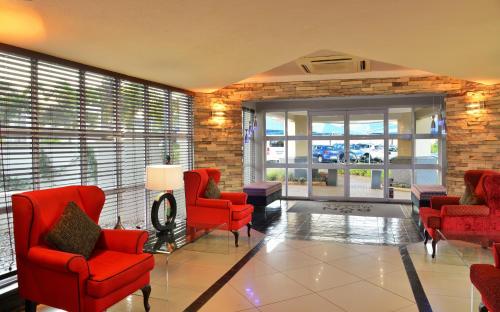 a living room with red chairs and a brick wall at BON Hotel Empangeni in Empangeni