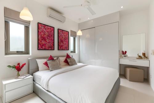 a white bedroom with a large white bed and two windows at Villa White Orchid in Choeng Mon Beach