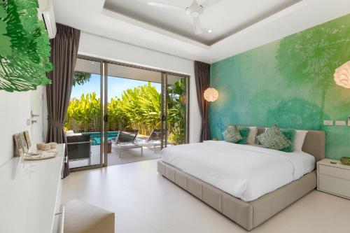 a bedroom with a large bed and a balcony at Villa White Orchid in Choeng Mon Beach