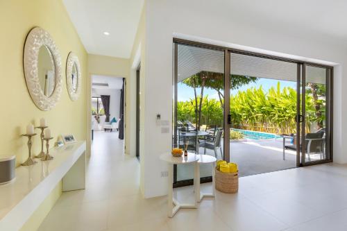 a living room with a table and a view of a pool at Villa White Orchid in Choeng Mon Beach