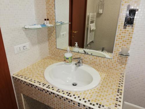 y baño con lavabo blanco y espejo. en Hotel La Vela, en Boscoreale
