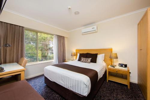 a hotel room with a bed, chair, and nightstand at Best Western Plus Hovell Tree Inn in Albury