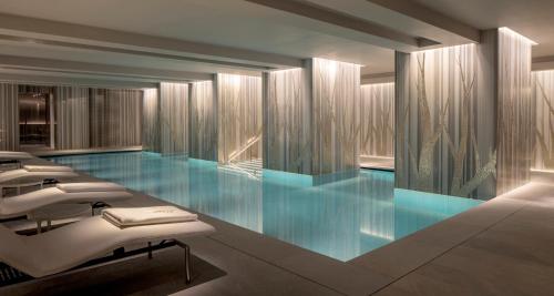 a swimming pool with blue water in a building at Four Seasons Hotel London at Ten Trinity Square in London
