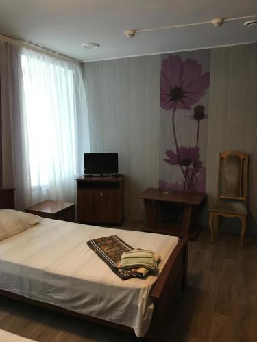 - une chambre avec un lit orné d'une fleur sur le mur dans l'établissement Восток, à Engels