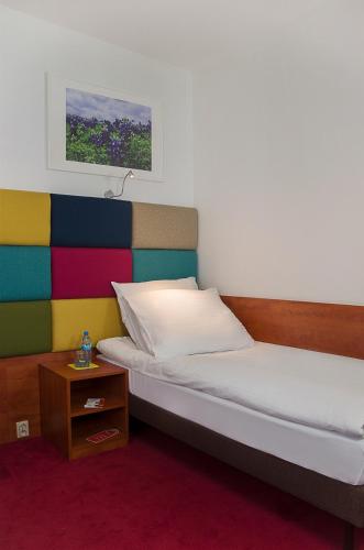 a bed with a colorful headboard and a night stand at euroHOTEL Sosnowiec Kazimierz in Sosnowiec